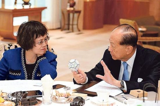 李嘉誠（右）在接受媒體訪問時指出，長實集團以香港為基地，常常積極在港尋找投資機會，但是政府很多政策，需時消化。圖為他向財新傳媒總編輯胡舒立介紹他本周的“最愛”納米LED燈泡。圖片來源：香港明報